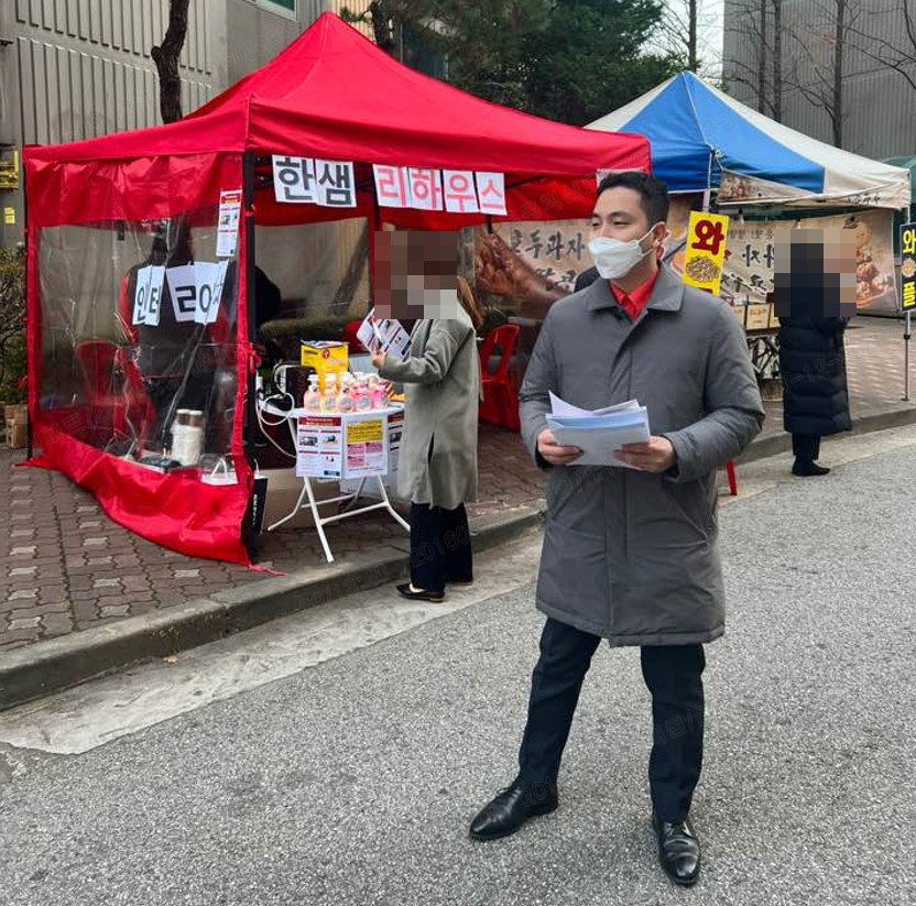 장터 천막 앞에서 전단을 들고 있는 대표
